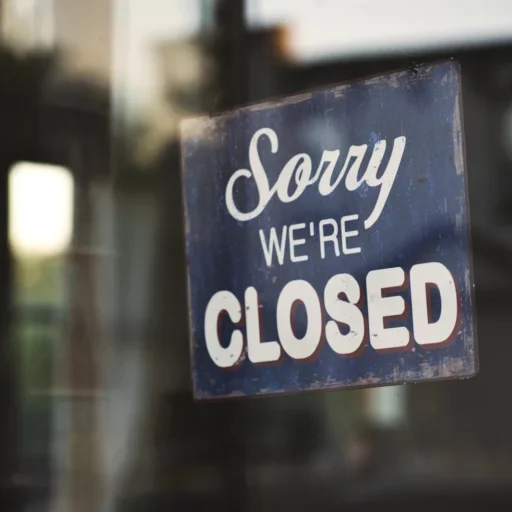 A Sorry We're Closed sign hanging in a glass shop door, the online equivalent of a business whose domain has lapsed